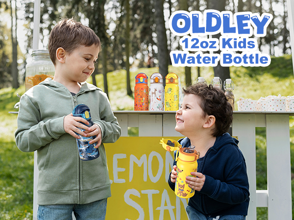 two young boys smiling at each other near a wooden lemonade stand in a park holding colorful insulated water bottles with trees in the background