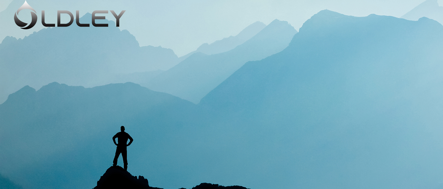 silhouette of person standing on mountain peak with layered blue misty mountains and logo