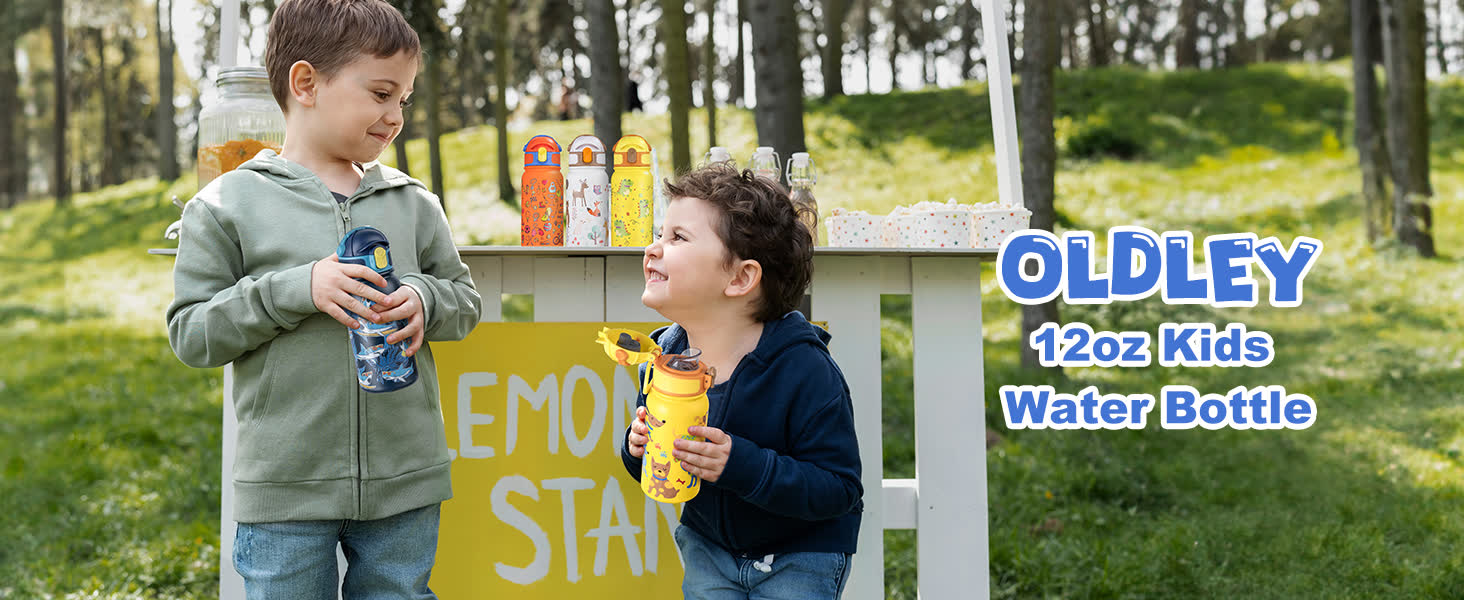 two young boys standing near a wooden lemonade stand outdoors holding colorful insulated water bottles with a grassy park and trees behind them